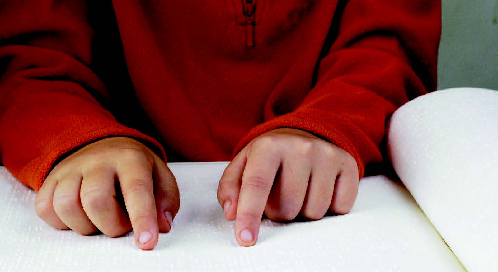 A child reads a book in braille.