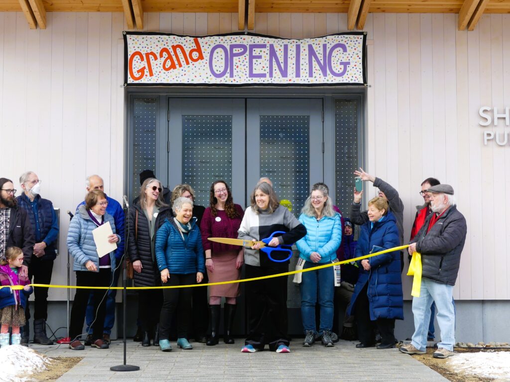 Library staff and community stand behind a yellow ribbon at the grand opening ceremony for the new Shutesbury Public Library on January 10, 2026.