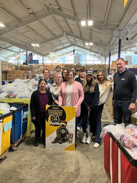 MBLC Staff and Bruins family members at Cradles to Crayons Warehouse with bins of donated clothes